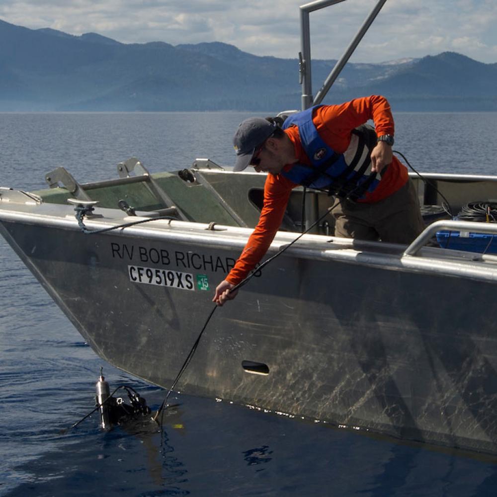 A researcher reaches into the waters of Lake Tahoe to secure a water sample