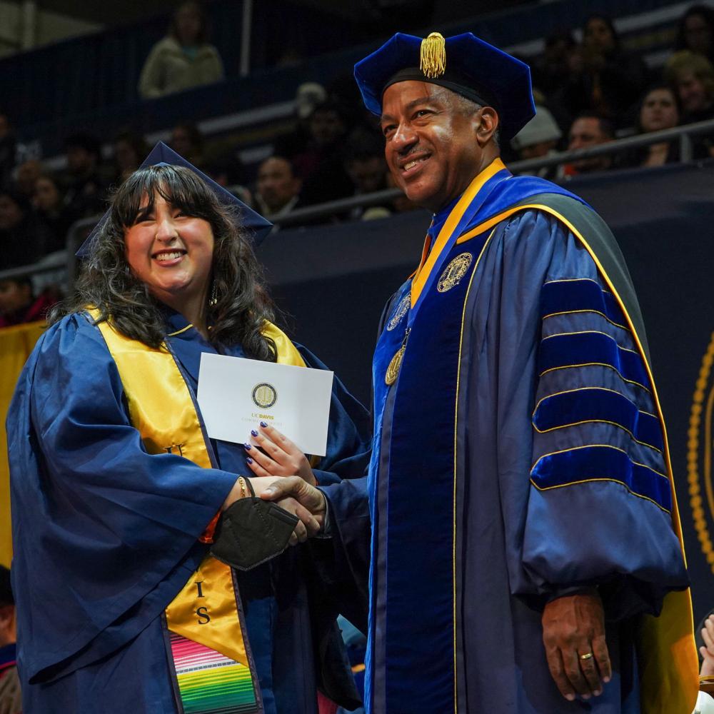 A UC Davis student shakes Chancellor May's hand at commencement