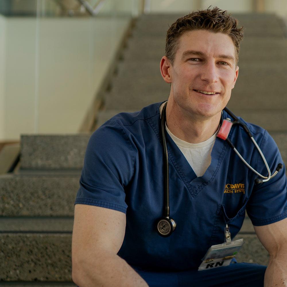 A male nurse sits on the stairs at the Betty Irene Moore School of Nursing