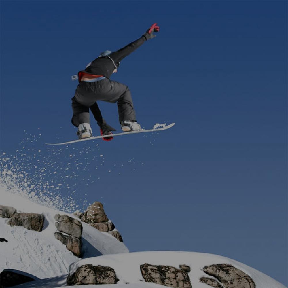 A snowboarder sends it off of a mountain peak