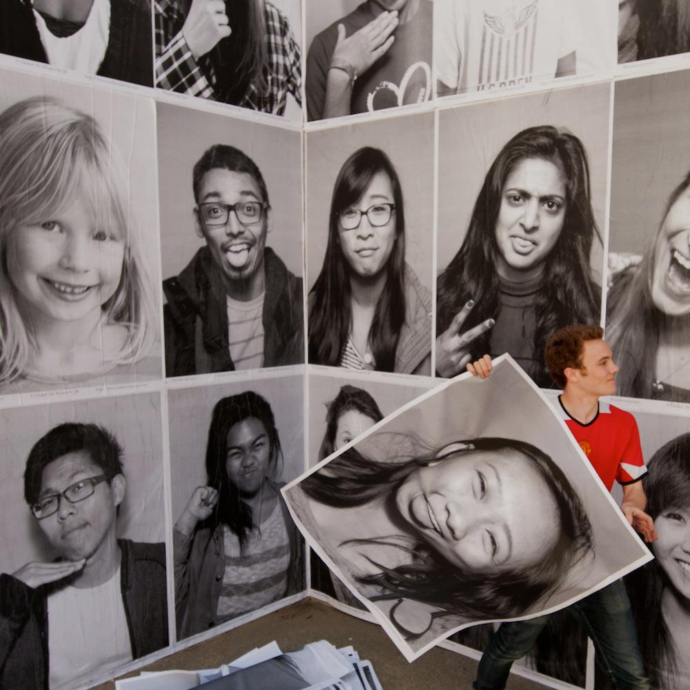 A student plasters several portrati pictures on the wall at the UC Davis social science building