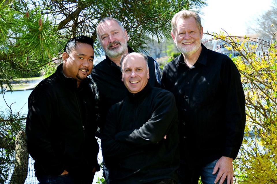 The members of the Alexander String Quartet wearing black and standing outside.