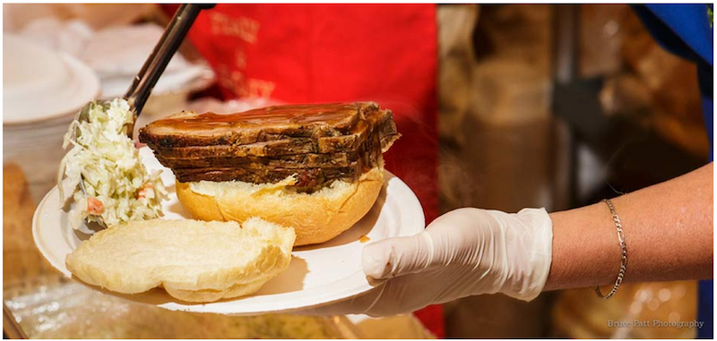 A photo of a brisket sandwich and coleslaw being served.