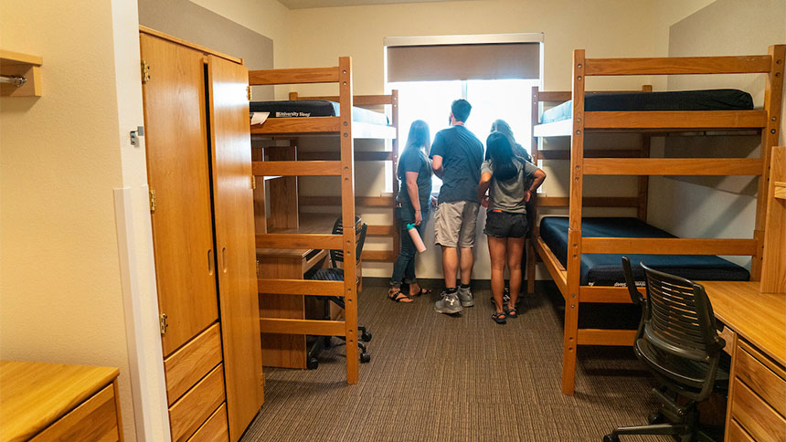 Four students look out a bedroom window.