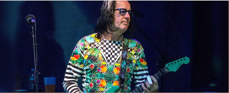 Todd Rundgren playing the electric guitar on stage.