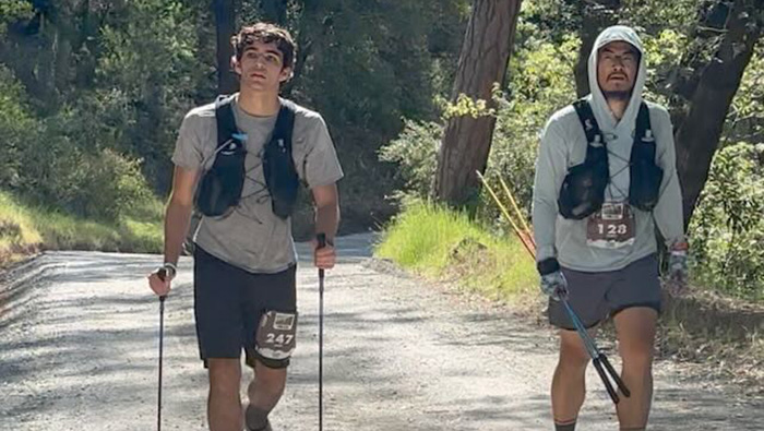 Ultramarathoners walk with poles in wooded area