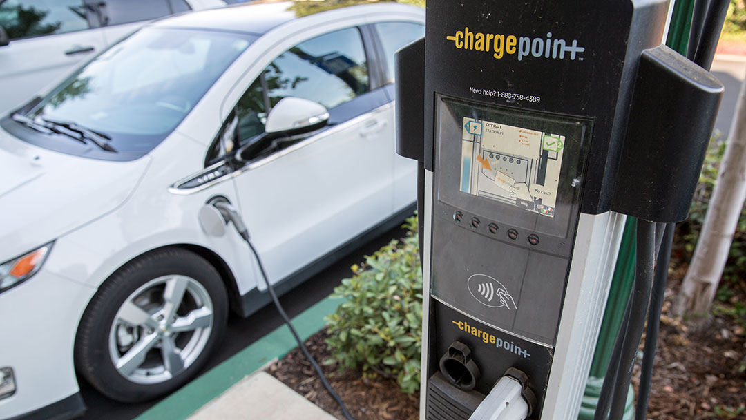 A white Chevrolet Volt is plugged in at a public Chargepoint charger.